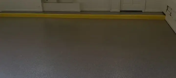 Gray epoxy garage floor with a yellow edge line