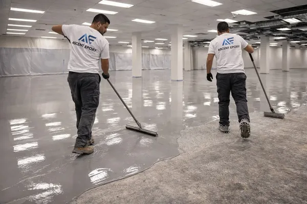 Crew spreading a gray epoxy coat across a commercial floor