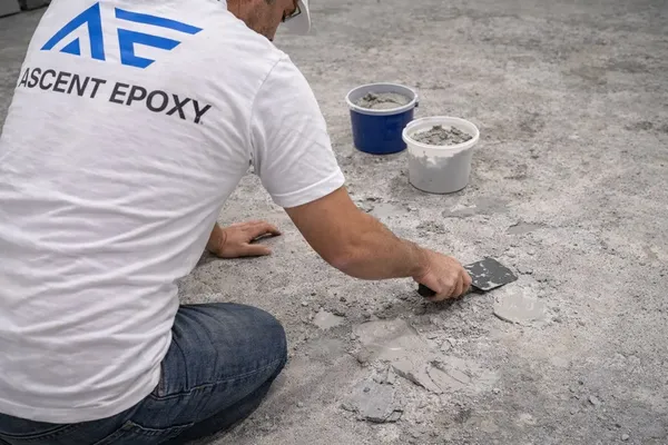 Crew member scraping off loose coating and patching the slab